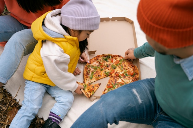 Free photo family eating pizza outdoors high angle