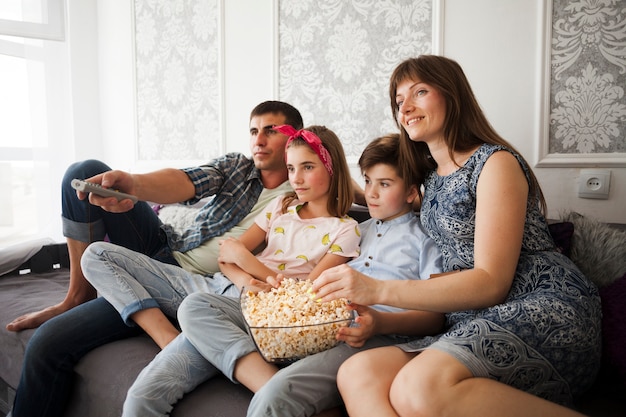 Free photo family eating popcorn during watching television at home