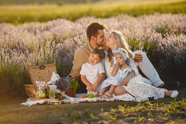 Family on lavender field. People on a picnic. Mother with children eats fruits.