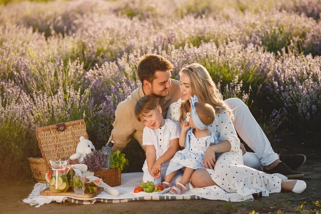 Family on lavender field. People on a picnic. Mother with children eats fruits.