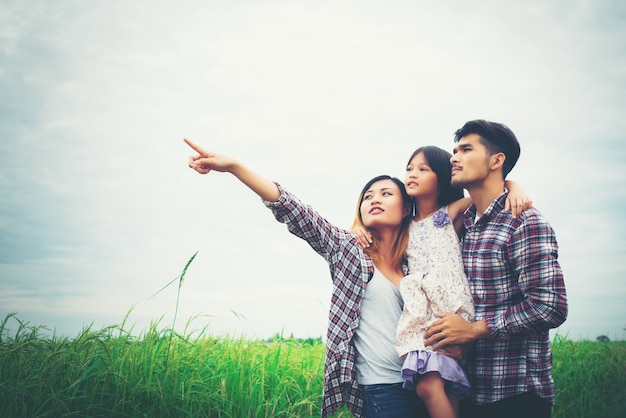 Family of mother, father and child on meadow, dad carrying the d