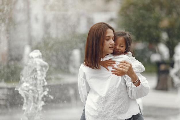 Family near the city fountain. Mother with gaughter playing with water.