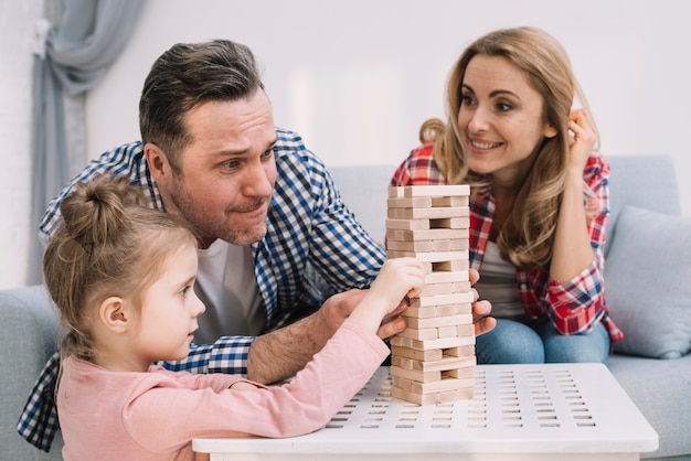 Family playing with block wooden game on table in living room