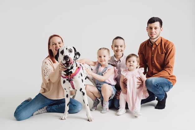 Family playing with a dalmatian dog on white background