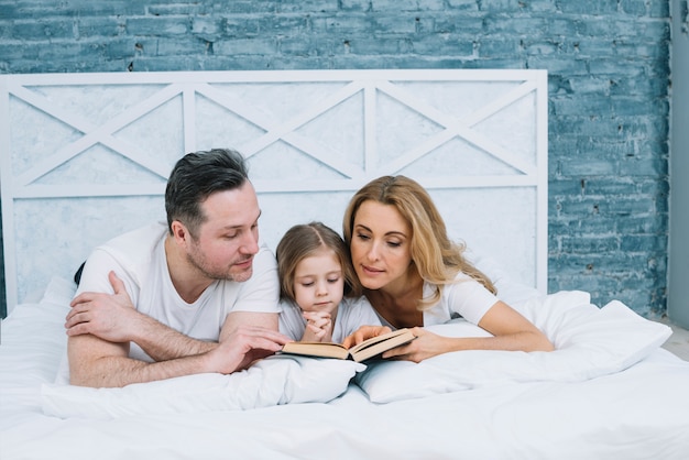 Free photo family reading book on bed