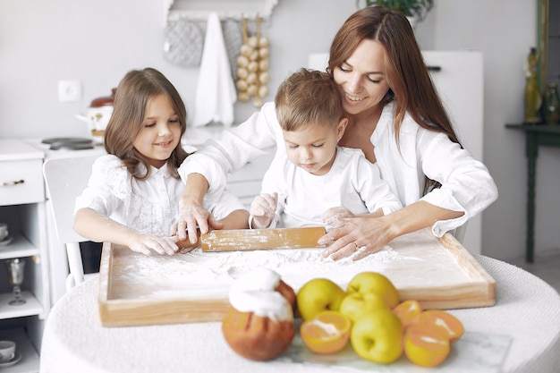 Family sitting in a kitchen and cook the dough for cake