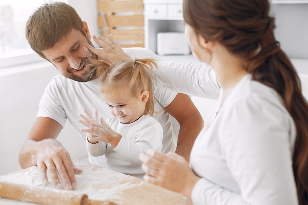 Family sitting in a kitchen and cook the dough for cookies