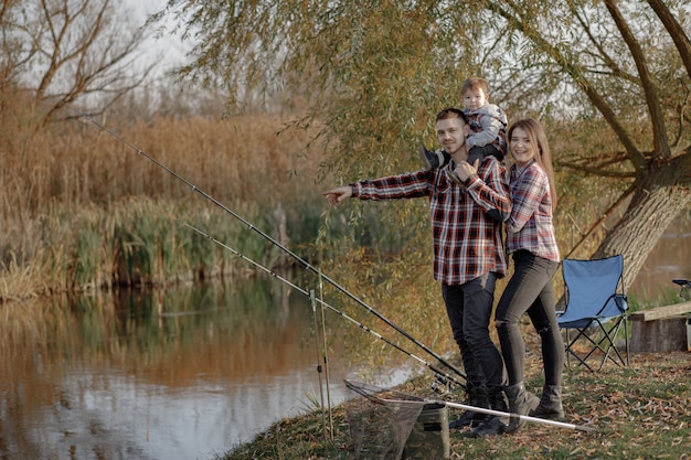 Family sitting near river in a fishing morning