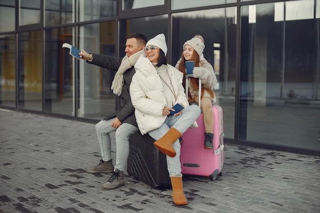 Free photo family sitting outdoors on a luggage and waiting for travel