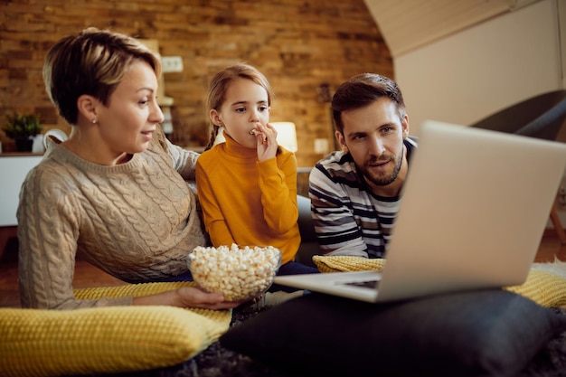 Free photo family using laptop while eating popcorn and relaxing at home