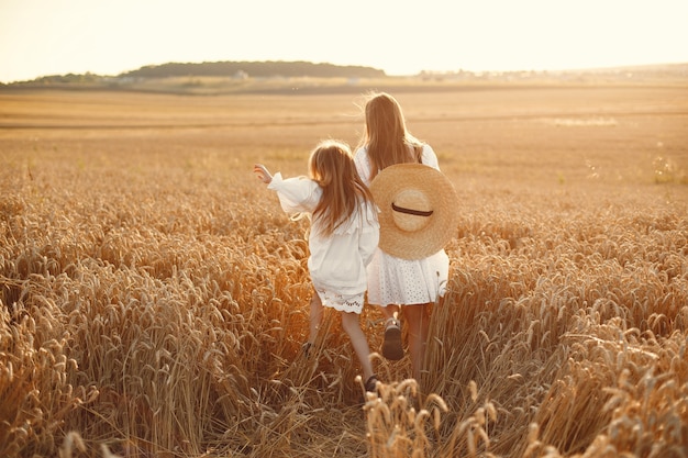 Family in a wheat field. Woman in a white dress. Girl with straw hat.