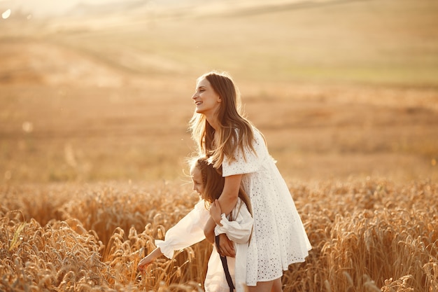 Family in a wheat field. Woman in a white dress. Girl with straw hat.