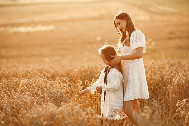 Family in a wheat field. Woman in a white dress. Girl with straw hat.