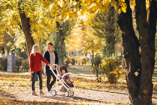 Family with baby daugher in a baby carriage walking an autumn park