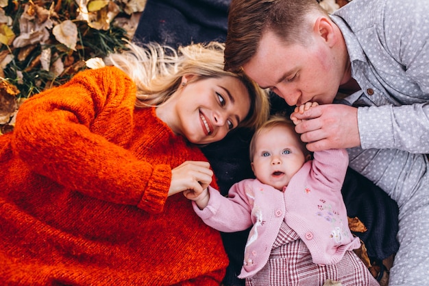 Family with baby daugher lying on leaves in park