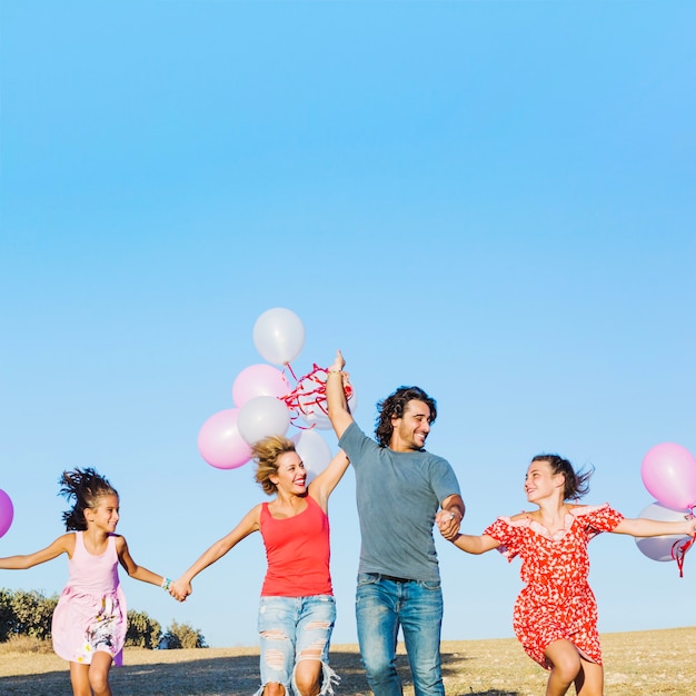 Family with balloons having fun in field