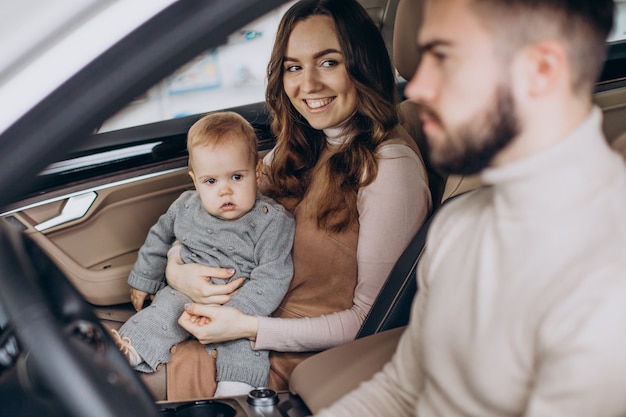 Free photo family with bbay girl choosing a car in a car saloon