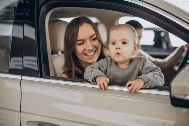 Family with bbay girl choosing a car in a car saloon