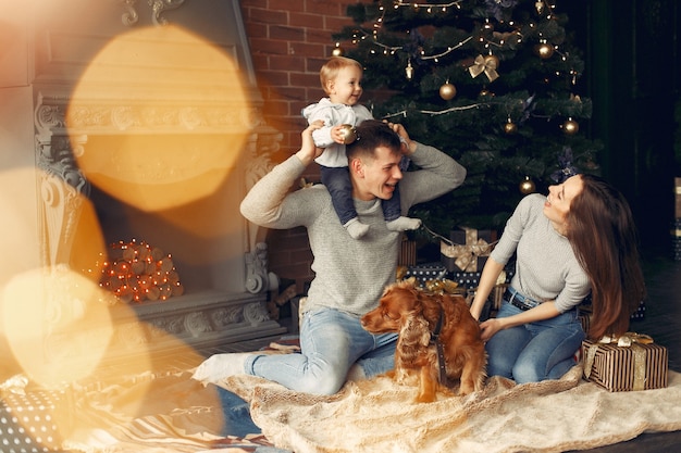 Family with cute dog at home near christmas tree