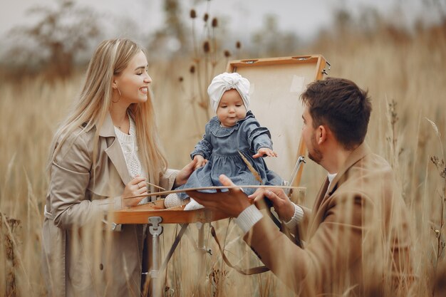 Family with little daughter painting in a autumn field