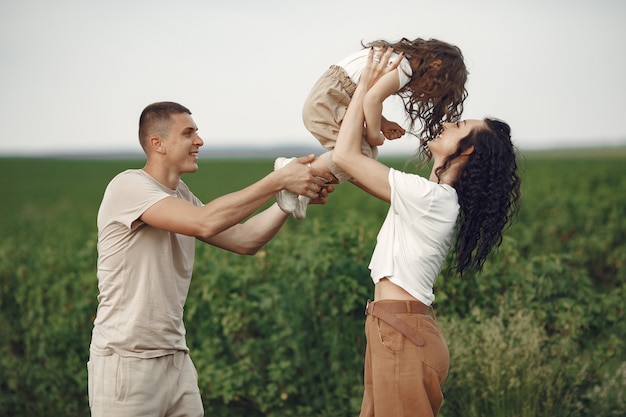 Family with little daughter spending time together in sunny field