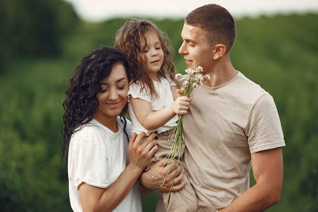 Family with little daughter spending time together in sunny field