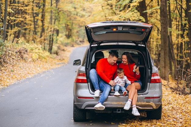 Family with a little son in autumn park sitting in car