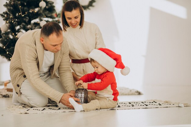 Family with little son by the Christmas tree at home