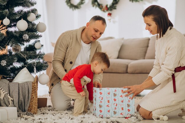 Family with little son on Christmas by christmas tree at home