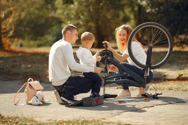 Family with son repare the bike in a park