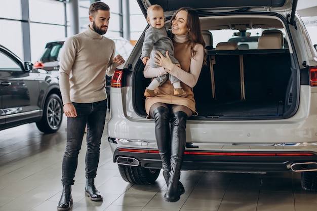 Family with toddler girl choosing a car in a car showroom