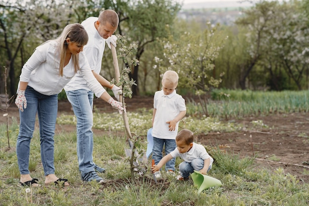 Free photo family with with little sons are planting a tree on a yard