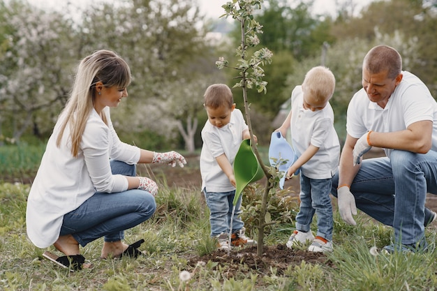 Free photo family with with little sons are planting a tree on a yard