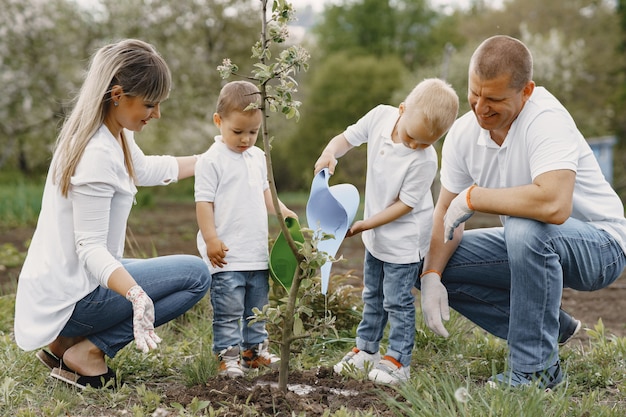 Free photo family with with little sons are planting a tree on a yard