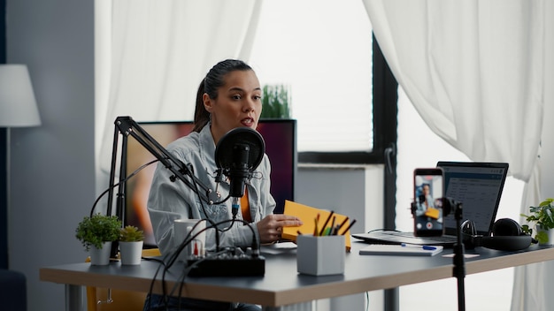 Free photo famous internet influencer filming agenda review while at home in studio. popular social media star doing notebook recommendation video while presenting product to audience.