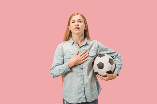 Fan sport woman player holding soccer ball isolated on pink studio background