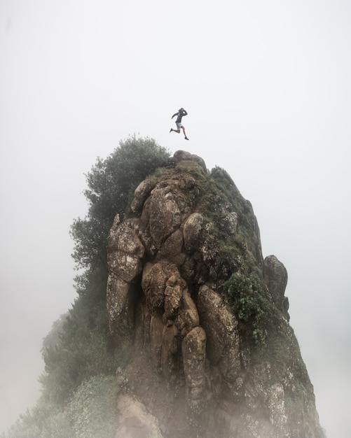 Free Photo fantasy concept - a person jumping over a high rocky cliff with a blurred foggy white background