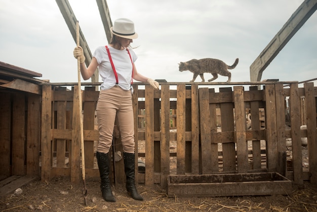 Free photo farmer cleaning a henhouse with a cat