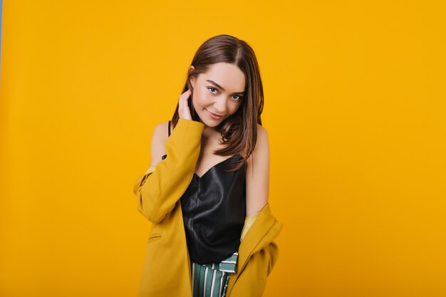 Fascinating caucasian woman expressing true positive emotions. Indoor portrait of pleased girl with brown hair smiling.