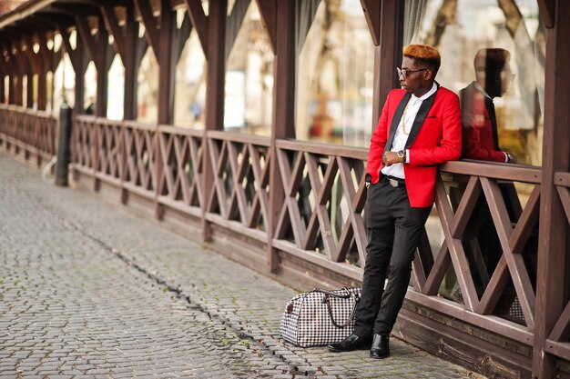 Fashion african american man model at red suit with highlights hair and handbag posed at street