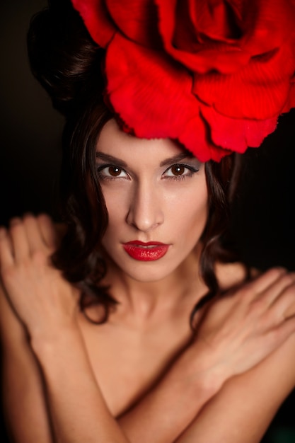 fashion beautiful woman with bright makeup and red lips with big red rose on head