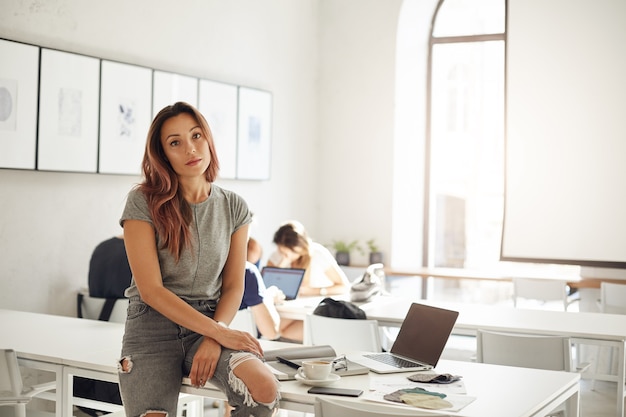 Free Photo fashion design apprentice studying in a coworking space or campus sitting on table with laptop and textile samples trendy professions concept.