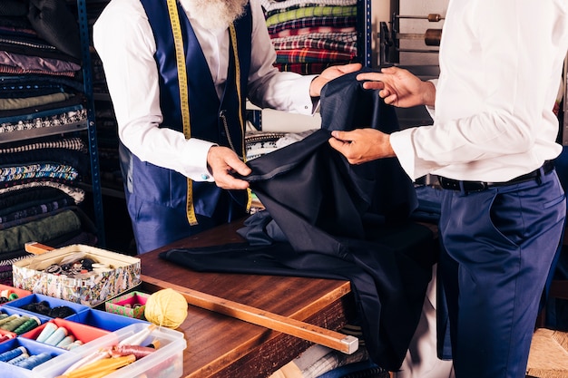 Fashion designer showing fabric to his customer in the shop