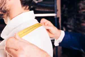 Free photo fashion designer taking measurement of his customer's back with yellow measuring tape