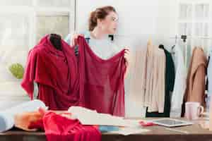 Free photo fashion designer woman working in studio sitting on the desk