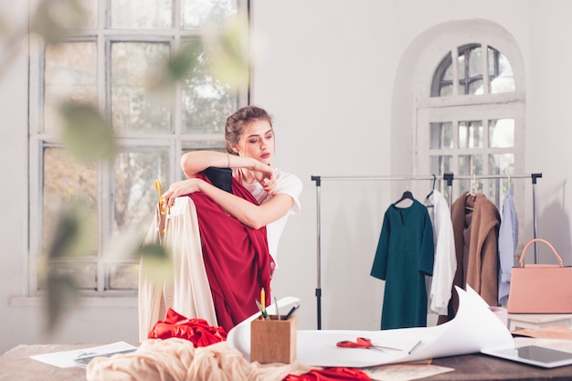 Fashion designer woman working in studio sitting on the desk