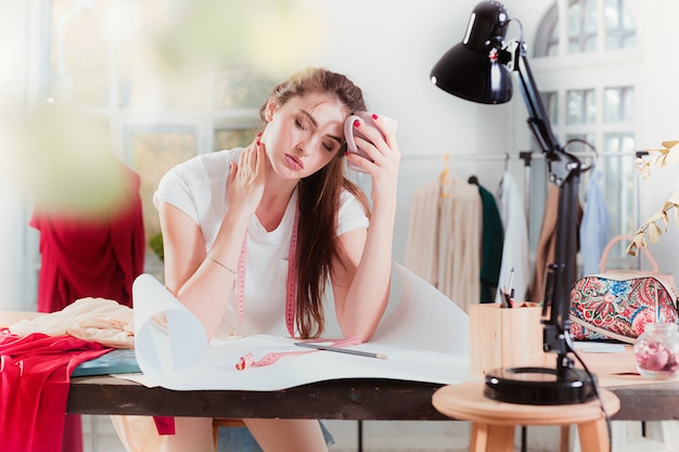 Fashion designer working in studio sitting on the desk