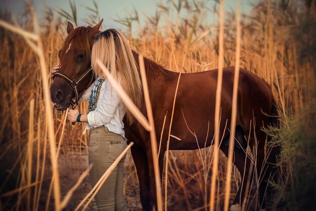 Fashion model in white dress walking with a horse