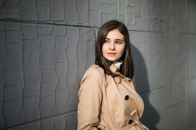 Fashion model with big eyes stays near grey wall outside