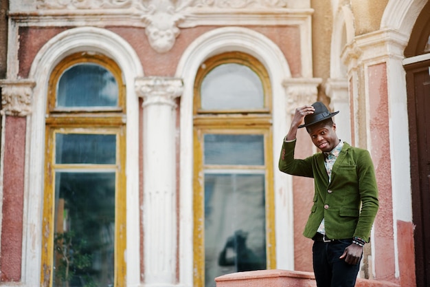 Free Photo fashion portrait of black african american man on green velvet jacket stay on stairs and wear his black hat background old mansion